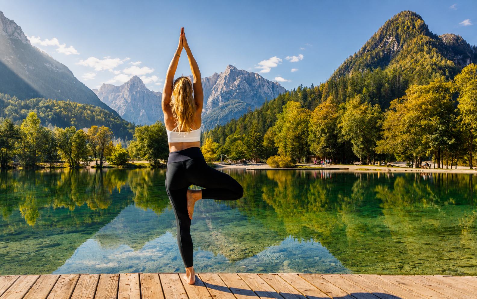 A woman in a yoga pose beside a still alpine lake